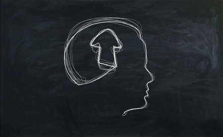 Male head outline with arrow on chalkboard background. Growth conceptの写真素材