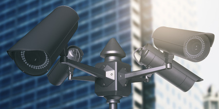 Black street cameras with blurry glass building in the background. CCTV concept. 3D Rendering