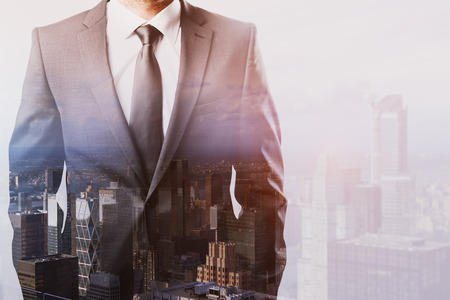 Unrecognizable businessman standing on abstract city background. Employment concept. Double exposureの写真素材
