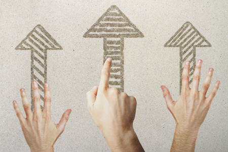 Hands pointing at drawn arrows on concrete background. Different direction conceptの写真素材