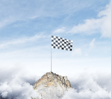 Checkered flag on mountain top. Cloudy sky background. Achievement concept の写真素材