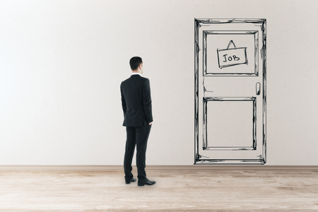 Young businessman in concrete interior looking at drawn foor with job banner. Opportunity and success concept. 3D Renderingの写真素材