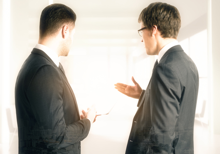 Back view of handsome european businessmen discussing contract in blurry bright office. Teamwork and finance concept. Double exposureの写真素材