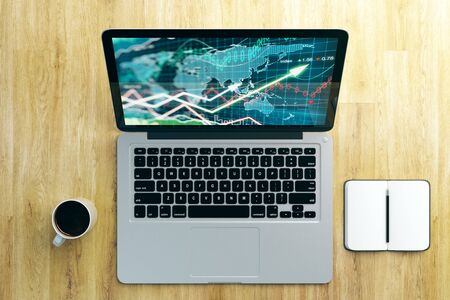 Top view of wooden desktop with forex chart on laptop screen, coffee cup and notepad. Workplace and investment concept. 3D Rendering の写真素材