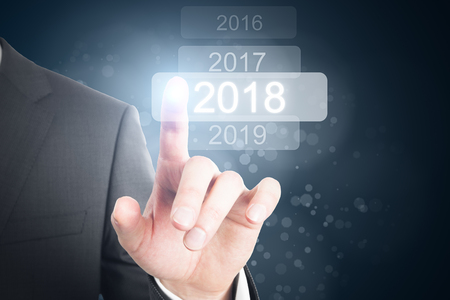 Businessman pointing at glowing digital 2018 touchscreen. Future and innovation backgroundの写真素材