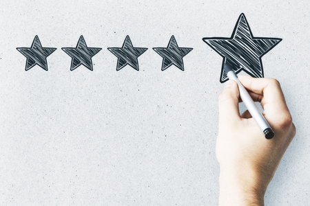 Businessman pointing at abstract stars on concrete wall background. Experience rating and exellence concept の写真素材