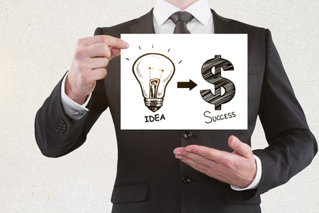 Businessman holding banner with business sketch on concrete wall background. Idea and money concept の写真素材