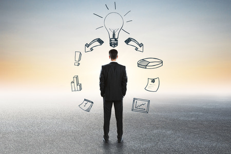 Back view of young businessman looking into the distance on abstract background with business sketch. Innovation and idea conceptの写真素材