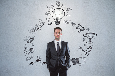 Presentation and solution concept. Portrait of handsome european businessman standing on concrete wall background with creative busines sketchの写真素材