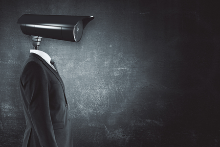 Side view of young businessman with CCTV camera head on concrete wall background with copy space for your text. Monitoring conceptの写真素材