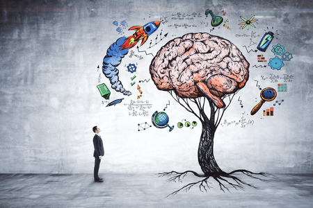 Businessman looking at abstract brain tree in concrete interior. Education, growth, brainstorm and startup concept