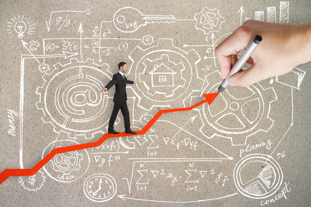 Businessman balancing on hand drawn arrows on concrete wall background with business sketch. Teamwork, economy and success concept の写真素材