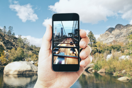 Hand taking photo of city with cellphone. Creative background concept の写真素材