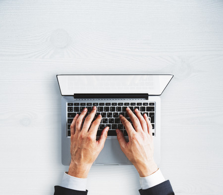 Top view of businessman hands using empty white laptop on concrete background. Mock upの写真素材