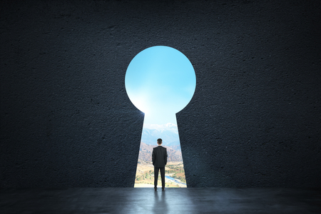 Back view of young businessman standing against keyhole door. Dream, success, opportunity and future conceptの写真素材