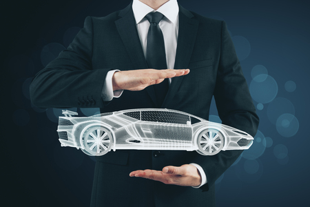 Businessman hand holding creative glowing sportscar hologram on blurry background. Transport, vehicle and engineer conceptの写真素材