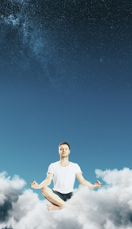 Meditating businessman in abstract starry sky with clouds. Dream and calm conceptの写真素材