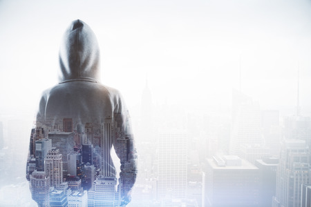 cyber attack concept with double exposure of back view hacker and blurred cityscape at background.の写真素材