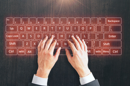 top view on businessman hands typing on virtual keyboard at wooden background.の写真素材