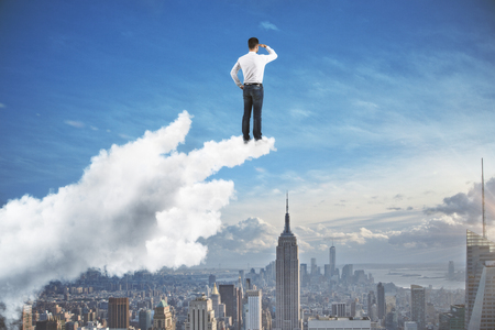 looking for decision concept with businessman standing on forefinger of cloud hand and staring into the distance at megapolis city backgroundの写真素材