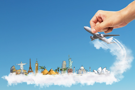 travel concept with businessman drawing famous city sights and hand controlling plane at blue sky backgroundの写真素材