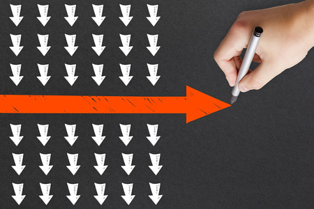 Hand drawing red arrow on concrete wall background. Leadership and follow concept