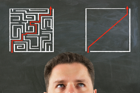 Handsome businessman half portrait on chalkboard wall background with maze sketch. Challenge and way conceptの写真素材