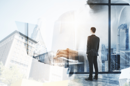 Businessman using laptop on abstract blurry office city background. Communication and technology concept. Double exposureの写真素材