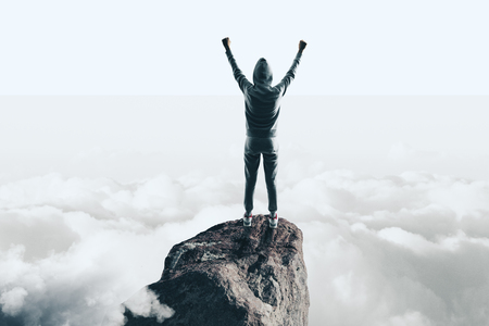 Back view of hacker celebrating success on mountain top. Sky background. Leadership, theft and phishing conceptの写真素材
