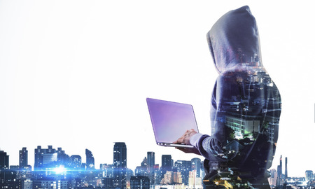Side view of hacker with laptop computer on city background with copy space. Hacking and computing...