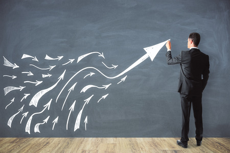 Businessman drawing arrows on chalkboard background. Future and forward conceptの写真素材