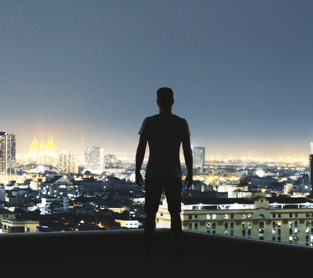 Back view of young backlit man looking into the distance on illuminated New York city background. Research and occupation conceptの写真素材
