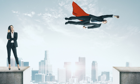 Businesswoman and flying superhero on rooftop. Teamwork and power conceptの写真素材