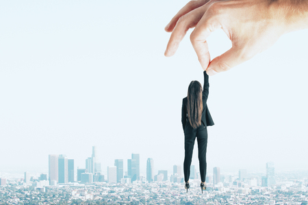 Teamwork and supervision concept. Hand holding businesswoman on sky and city backgroundの写真素材