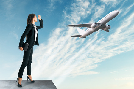 Businesswoman looking at flying by airplane. Travel and vision conceptの写真素材