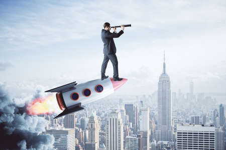 Businessman on rocket looking into the distance with telescope on light city background. Startup and...