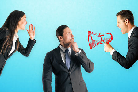 Businesspeople shouting at young european businessman using speaker. Teamwork and education conceptの写真素材