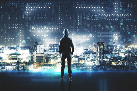 Back view of young hacker standing on abstract city circuit background. Hacking and phishing concept. Double exposureの写真素材