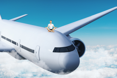 Young man meditating on airplane. Sky background. Freedom and transport concept.の写真素材