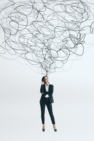 Thoughtful young businesswoman with scribble standing on white background. Confusion and solution conceptの写真素材