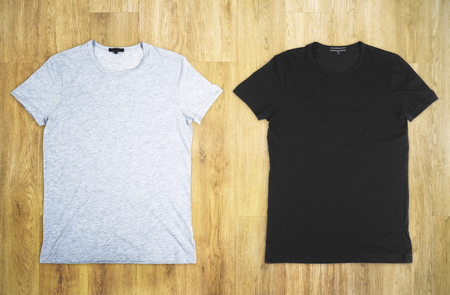 Empty grey and black t-shirts (back and front) on wooden background. Advertising and fashion concept. Mock upの写真素材