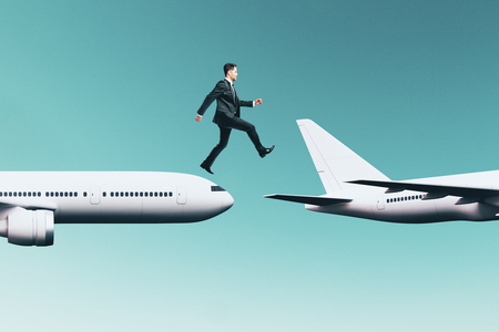 Businessman jumping from plane to plane on sky background. Travel and transport concept.の写真素材