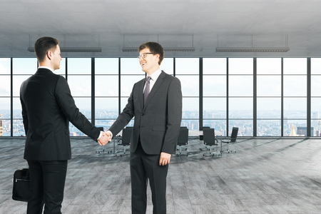 White  businessmen shaking hands in modern office interior. Teamwork and success concept.の写真素材