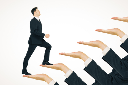 Businessman climbing hand ladder on white background. Career development and promotion conceptの写真素材