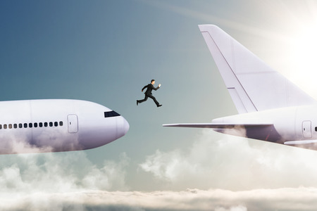Side view of young businessman jumping from plane to plane. Challenge and travel conceptの写真素材