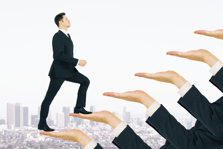 Businessman climbing hand ladder on white city background. Career development and future conceptの写真素材
