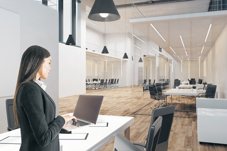 Caucasian businesswoman using device in modern office interior. Technology and communication concept.の写真素材