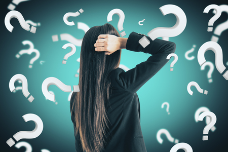 Portrait of attractive young european businesswoman with question marks. Doubt and stress conceptの写真素材