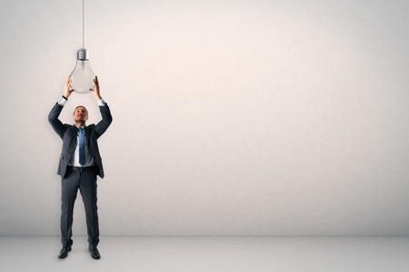 Attractive young european businessman holding lamp on white background. Innovation and solution conceptの写真素材