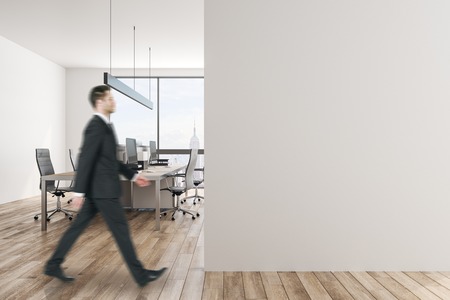 Young businessman in white office interior with copy space on wall and daylight. Mock up,の写真素材